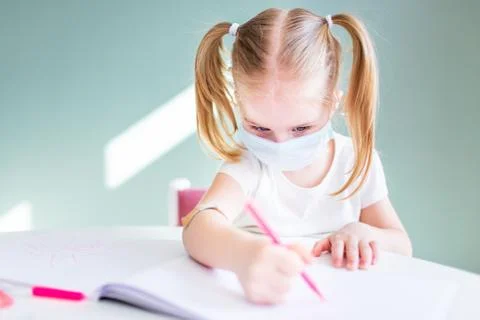 Home schooling learning during virus pandemic. Little girl drawing at home, w Stock Photos