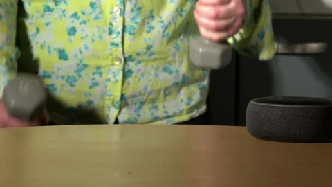 Home smart voice device in home with woman exercising in background Stock Footage 230485558