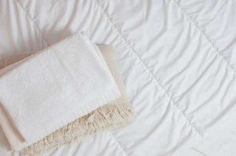 Home textiles Flatlay. A stack of towels lies on a white bed Stock Photos