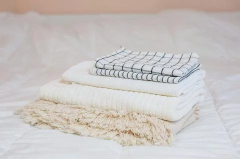 Home textiles. A stack of towels lies on a white bed Stock Photos