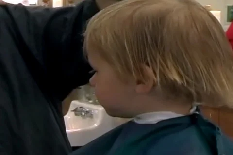 Home video of a two-year-old blonde boy getting his first haircut. Stock Footage 107281124