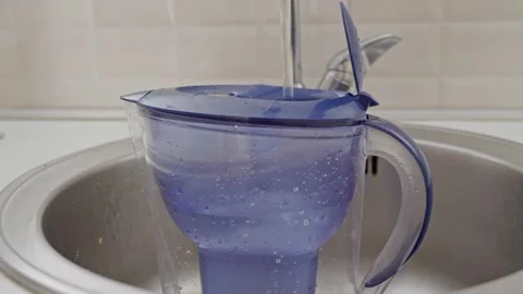 A home water filter is in the sink in the kitchen and cold tap water is poured Stock Footage 202076595