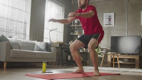 Home workout. Young bearded man doing squats exercises, sports training alone Stock Footage 169016727