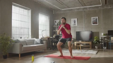 Home workout. Young bearded man doing squats exercises, sports training alone in Stock Footage 169017067