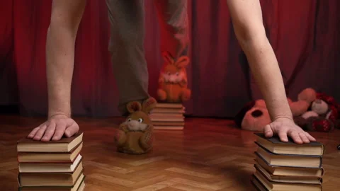 Home Workout.Man performs push-ups using three stacks of books. Stock Footage 131095863