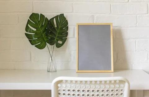 A home workplace.An empty picture frame or photo and monstera leaves in a vas Foto stock