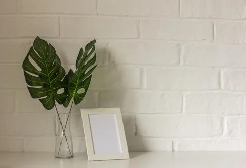 A home workplace.An empty picture frame or photo and monstera leaves in a vas Foto stock
