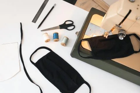 Home workplace with sewing machine,  threads, protective mask on white back Stock Photos