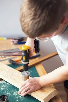 Home workshop. Close-up of a man in goggles working with a drill. Stock Photos