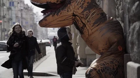 Homeless boy talking to man in dinosaur mascot costume at sidewalk Stock Footage 84929918