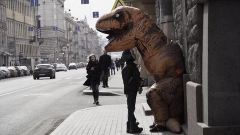 Homeless kid talking to man in dinosaur mascot costume at sidewalk Stock Footage 84929854