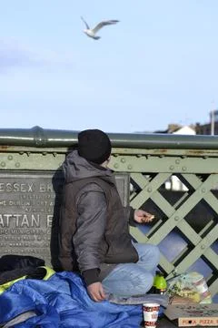 Homeless man on a bridge watching seagulls in Dublin, Ireland. Stock Photos