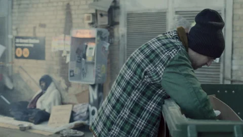 Homeless Man Digging through Trash Bin on Urban Street Stock Footage 313644682