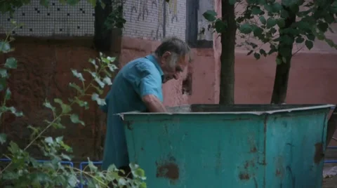 Homeless man looking for food in garbage Stock Footage