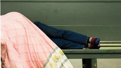 Homeless man lying at the bench Stock Photos
