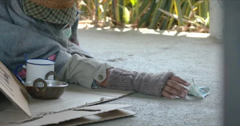 Homeless man is lying down on sidewalk is asking for money Stock Footage 139851538