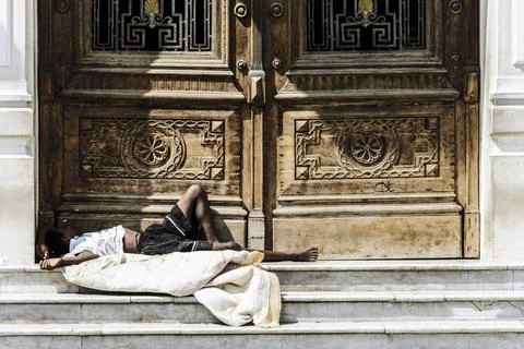 Homeless man sleeping at the door of a historic building Stock Photos