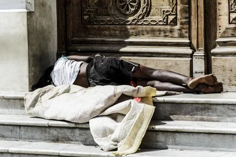 Homeless man sleeping at the door of a historic building Stock Photos