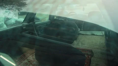 Homeless man sleeping inside car back seat, view through dirty rear window of Stock-Footage 323910911