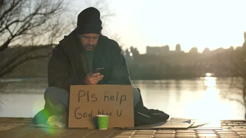 Homeless man using mobile phone while begging Stock Footage 88876257