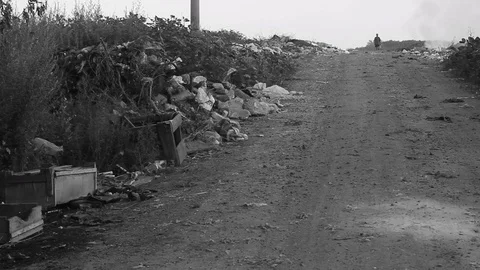 A homeless man walks through a garbage dump. Ecology concept Stock Footage 129082420