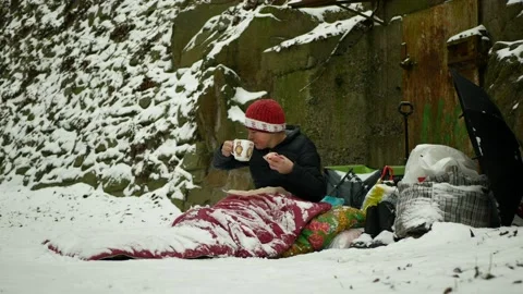 Homeless poor food rolls eats pastry ham meat drinks tea park winter snow frost Stock Footage 148402962