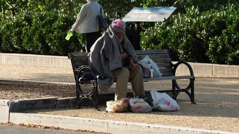 Homeless senior man sitting on bench in park Stock Footage