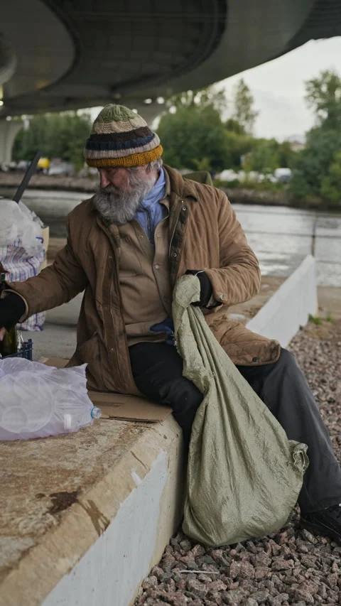 Homeless Senior Man Sorting Recyclable Bottles under Urban Bridge Stock Footage 345714771