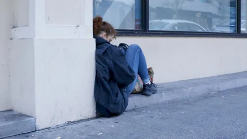 Homeless woman sitting on sidewalk Stock Footage
