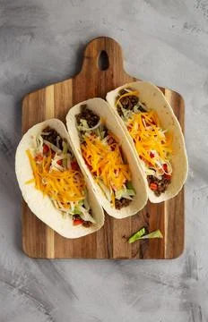 Homemade American Beef Tacos with lettuce, tomato and cheese on a wooden bo.. Stock Photos