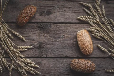 Homemade bread with wheat ears on rustic wooden table. Stock Photos