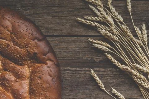 Homemade bread with wheat ears on rustic wooden table. Stock Photos