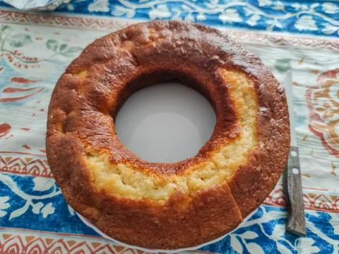 Homemade bundt cake on patterned tablecloth with knife Stock Photos
