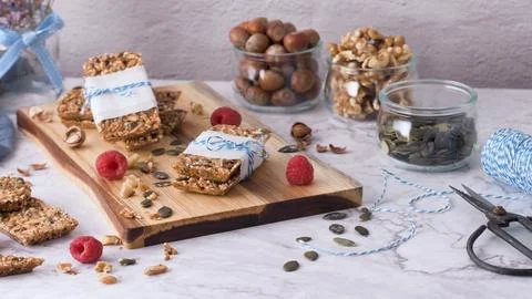 Homemade cereal bars wrapped with string on a wooden board with nuts and seed Stock Photos