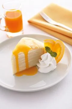 Homemade cheese crepe cake with orange sauce on table, vertical view. Stock Photos