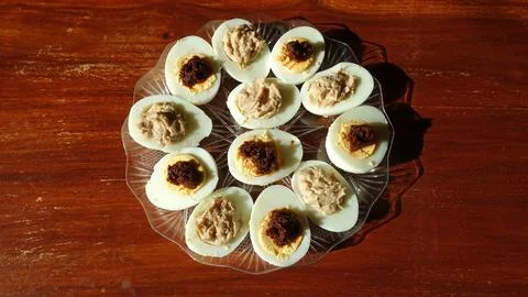 Homemade Deviled and Tuna Stuffed Eggs Platter on Glass Plate Over Wooden Tab Stock Photos