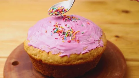 Homemade glazed pink easter pie decorating with dragees on wooden board. Stock Footage 129777062