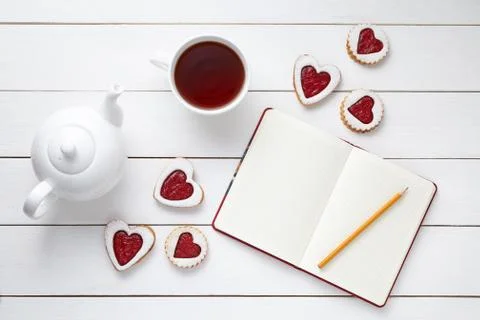 Homemade heart shaped cookies with empty notebook, pencil, cup of tea and teapot Stock Photos