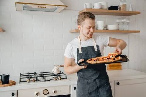 Homemade Italian pizza, handsome young male chef in dark apron holds baking Stock Photos