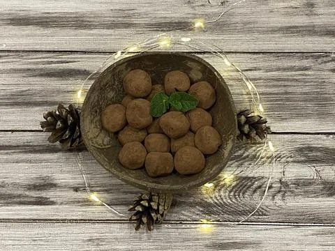Homemade pine nut candy with dates and cocoa in a round plate on a wooden bac Stock Photos