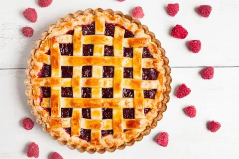 Homemade raw raspberry pie greased with egg yolk and jam on white kithen table Stock Photos