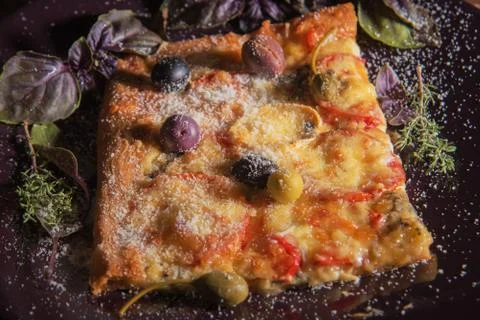 Homemade rectangular pizza on the dark plate with olives and parmesan cheese  Stock Photos