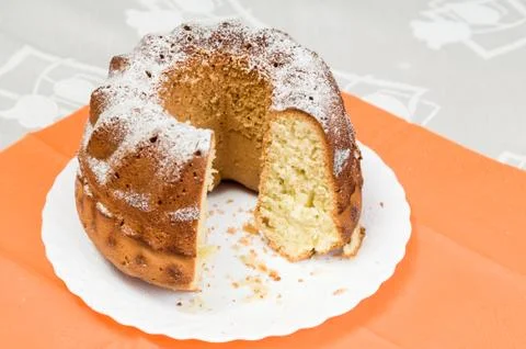 Homemade ring cake dusted with icing sugar on white plate Stock Photos