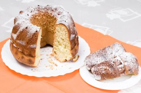 Homemade ring cake dusted with icing sugar on white plate Stock Photos