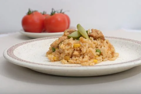 Homemade risotto with corn, peas and chicken on a plate on the table Stock Photos