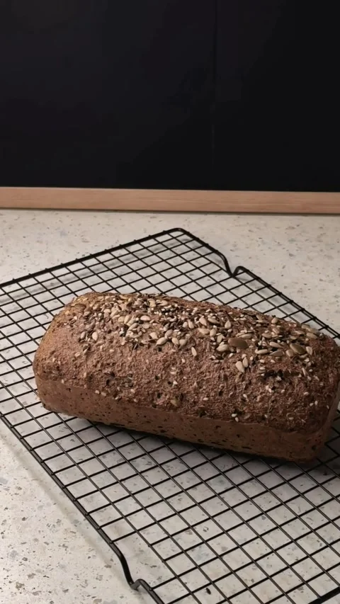 Homemade seeded bread loaf cools on a wire rack after baking, fresh rustic Video stock 344532725