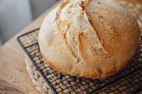 Homemade sourdough bread cooling on a rack on a rustic wooden table Stock Photos
