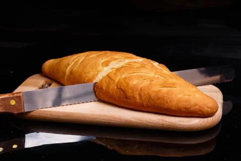 Homemade white bread is cut with a large knife. Baking at home. Foto stock