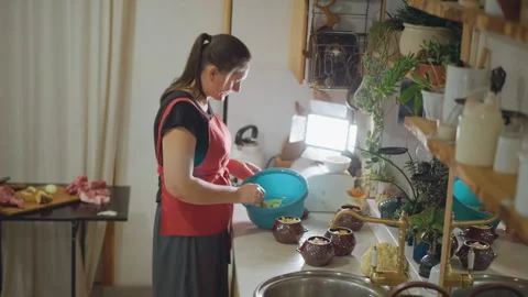 Homemaker assembling dinner amidst kitchen clutter. Authentic kitchen routine Video stock 348297475