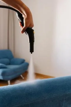 Homemaker using steam cleaning machine, removing tough stains from upholstered Stock Photos